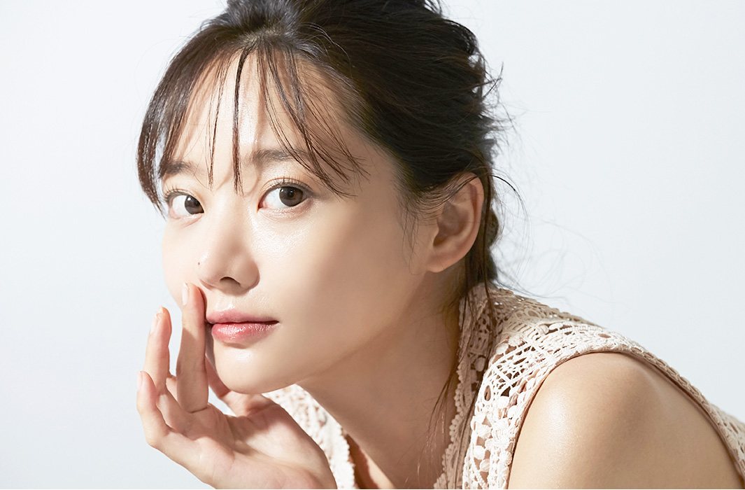 손가락을 볼에 대고 정면을 보는 앞머리 여성 모델