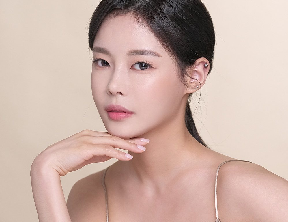 손을 턱에 댄 묶음머리 여성 모델(살구빛 바탕)